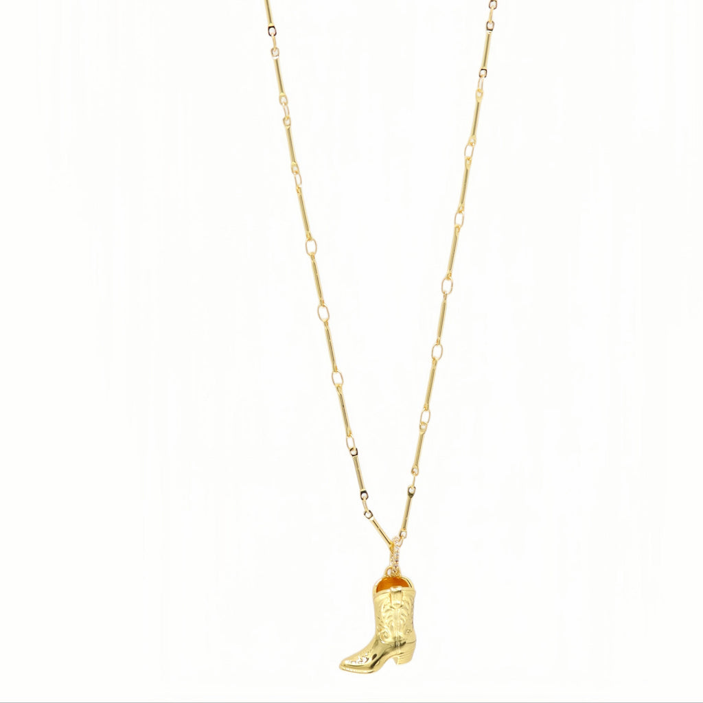 A gold chain necklace featuring a small cowboy boot pendant with a textured western design and a tiny orange accent near the top of the boot, shown against a plain white background.