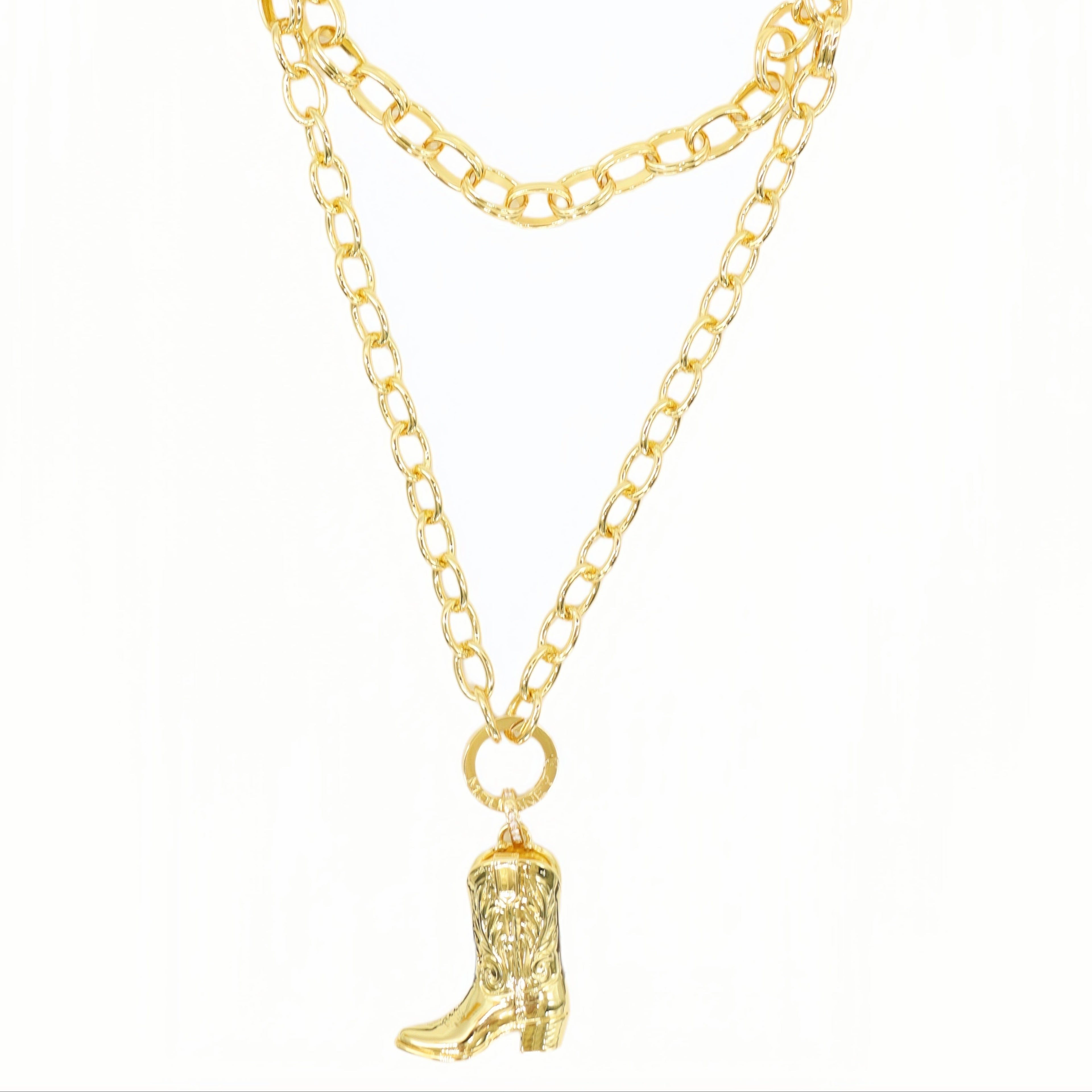 A gold-toned double-layered chain necklace featuring a small cowboy boot charm, displayed against a plain white background.