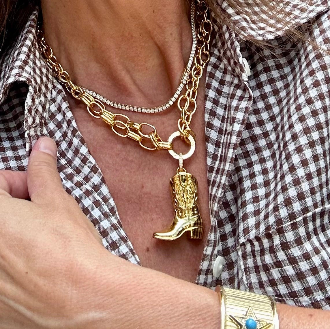 A large gold cowboy boot charm hanging from a golden chain
