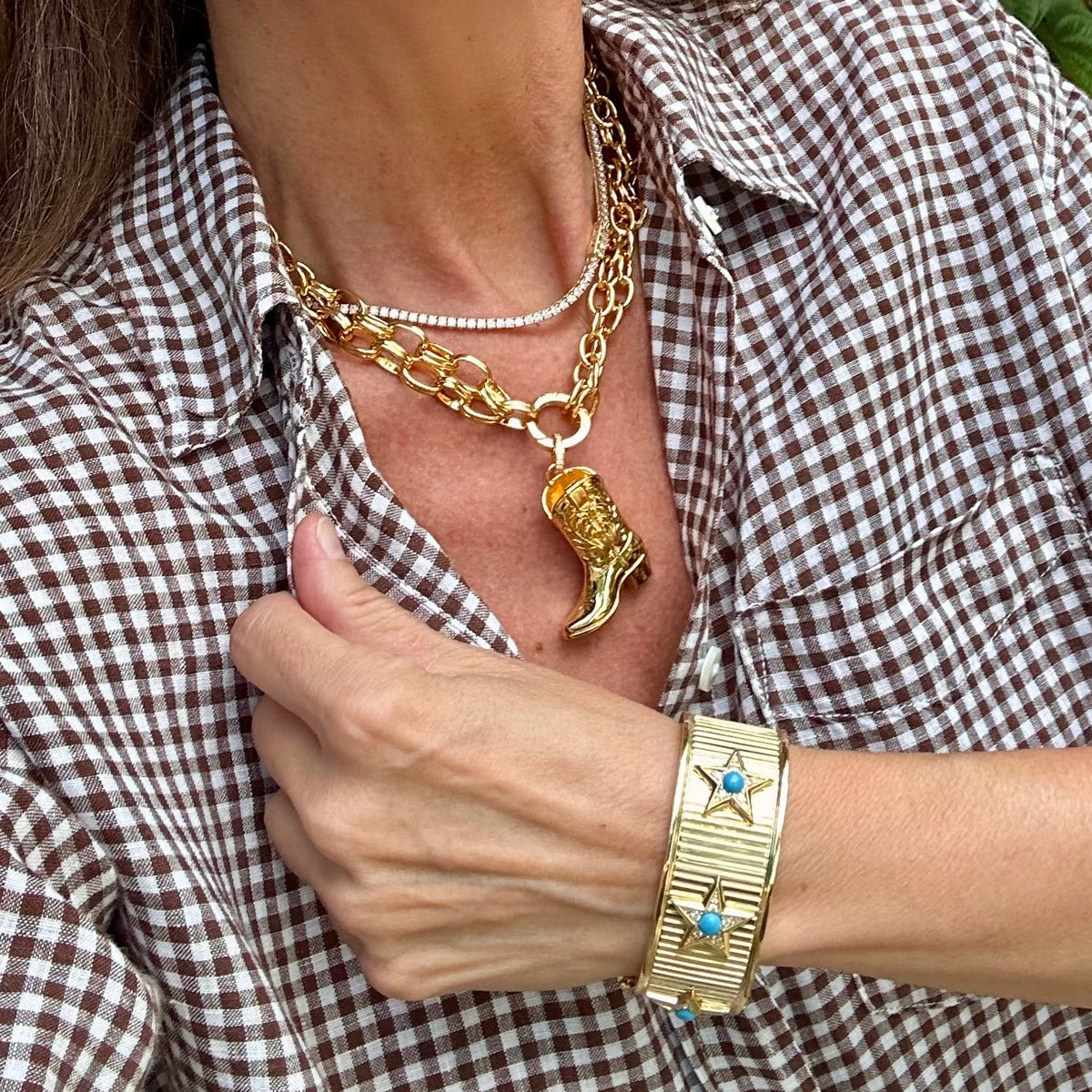Woman wearing a cowboy boot large charm hanging from a chunky necklace