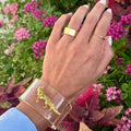 A clear cuff bracelet with a golden fox design with bright colored flowers in the background