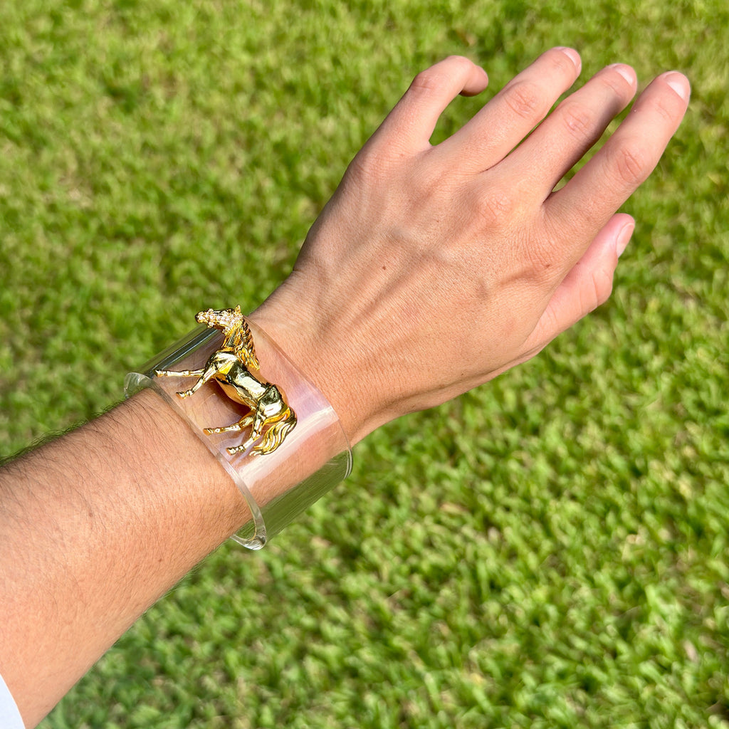 Gold horse charm on a clear cuff bracelet