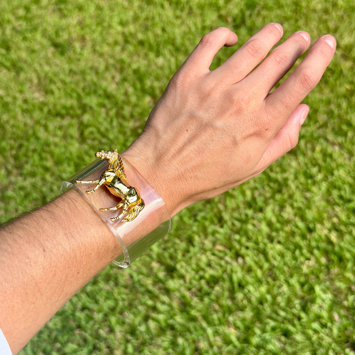 Gold horse charm on a clear cuff bracelet